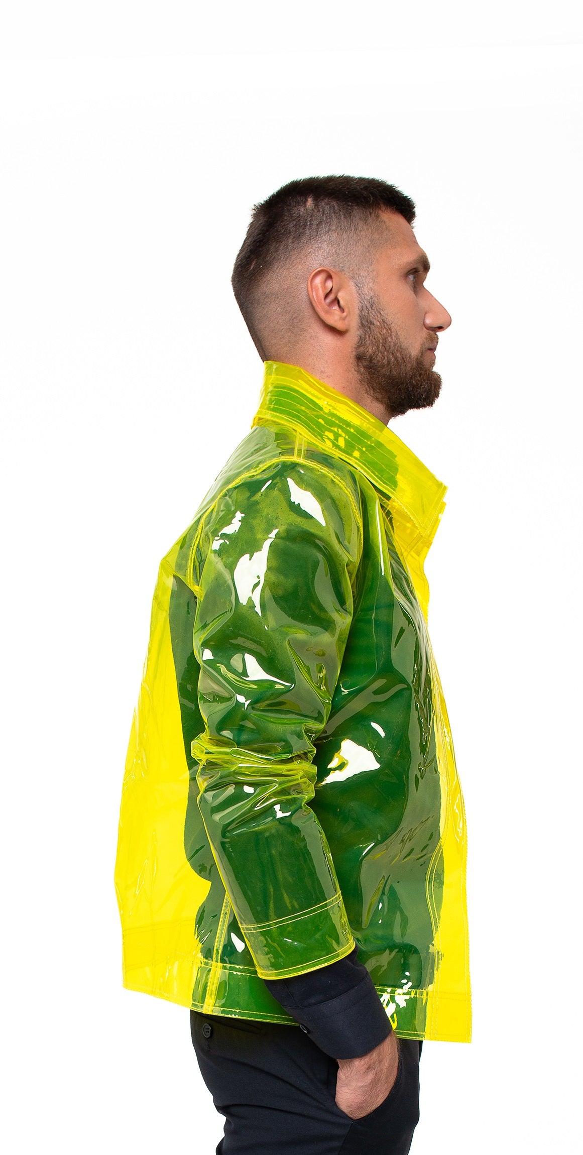 Model wearing transparent yellow raincoat with protective high collar over black outfit.