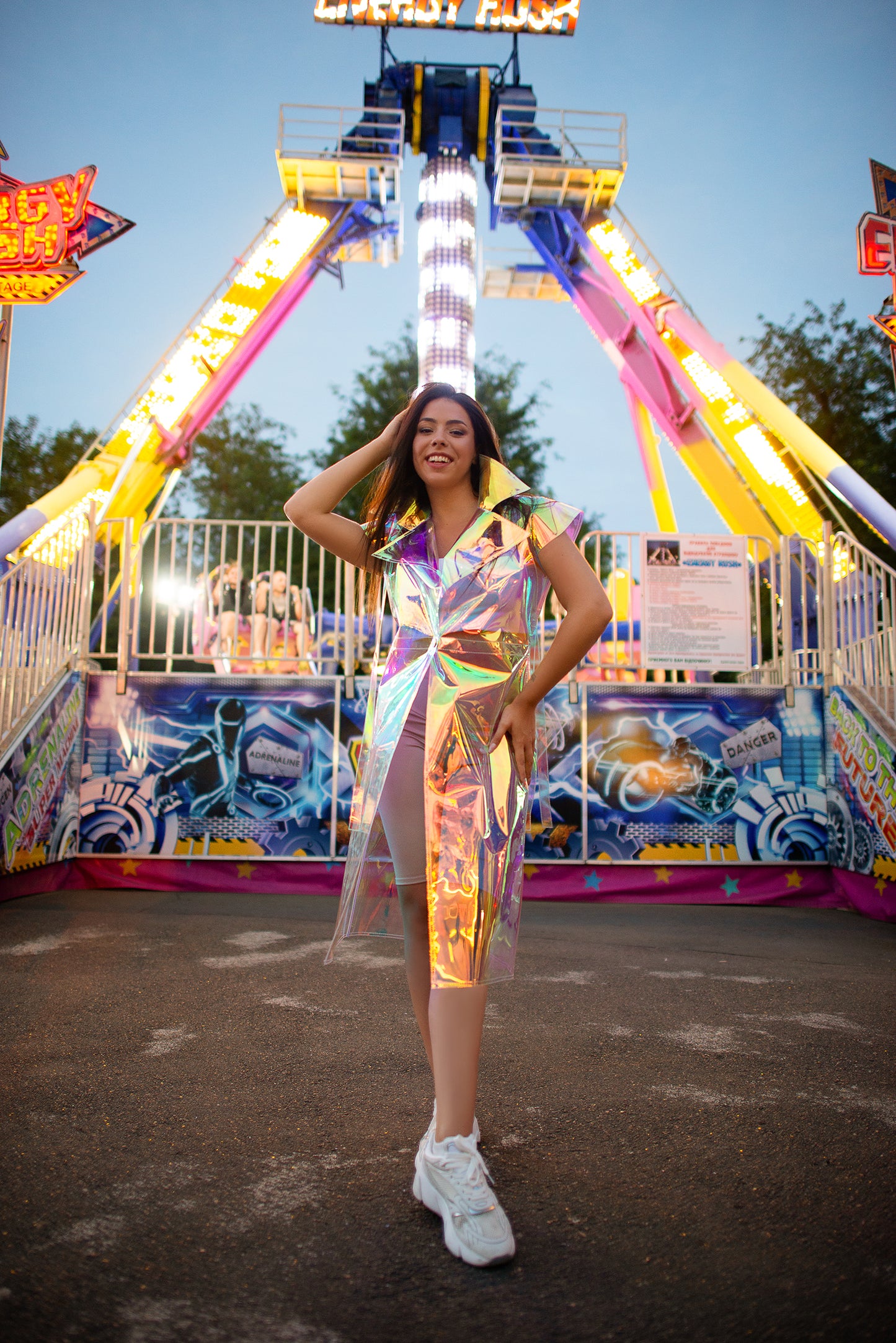 Model wearing a futuristic iridescent longline vest at a festival.