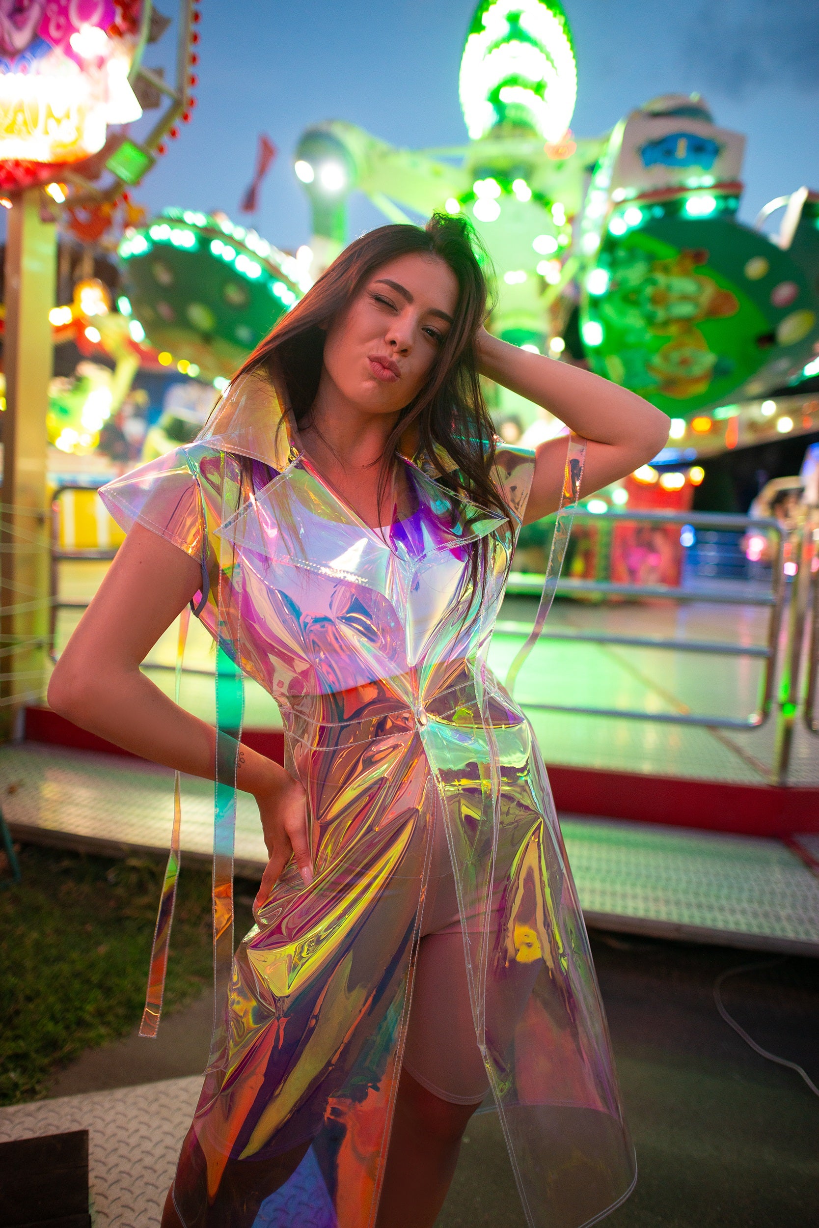 Model wearing a futuristic iridescent longline vest at a festival.