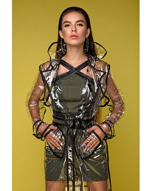Woman wearing a transparent raincoat over a green outfit against a yellow background