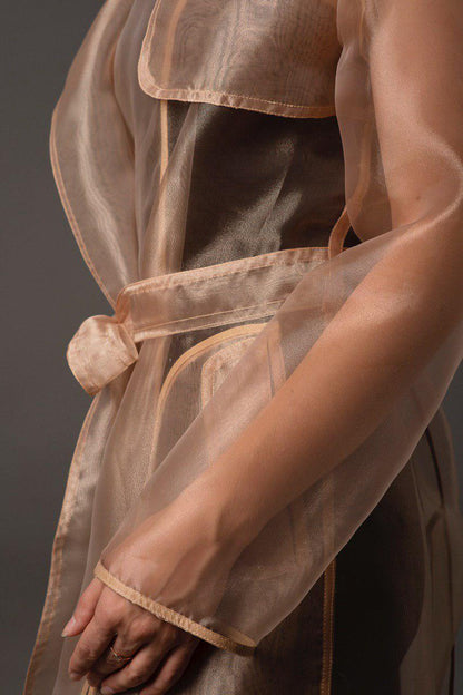 Person wearing a sheer beige apron with a dark background